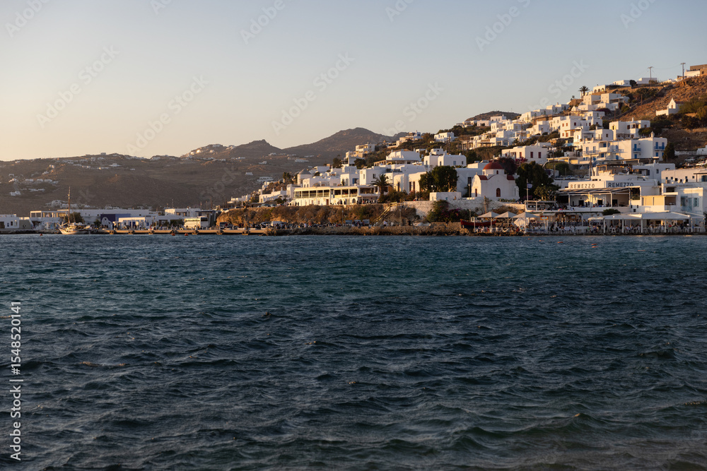 View of Mykonos coastline from a yacht in early evening golden light. View of Mykonos coastline from a yacht in early evening golden light.