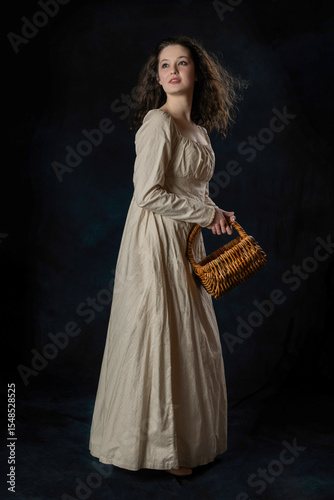 A Regency woman wearing a cotton dress with her long hair blowing in the wind against a studio backdrop