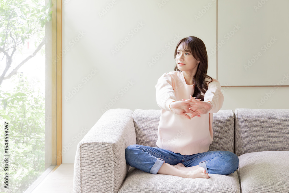ソファでストレッチをする女性 ソファでストレッチをする女性