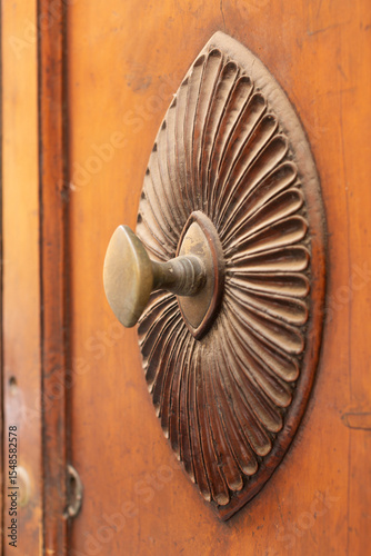 Ornate door handle with wooden background pattern and metal knob handle