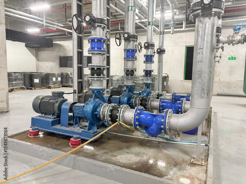 Large industrial pumps and insulated piping system in a modern chiller plant. Key components for thermal energy transfer and HVAC operations in commercial or industrial facilities.