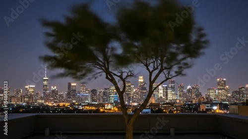 Tree moves in wind on rooftop against glowing night city skyline with vibrant lights. Urban motion concept seamless looping 4k time-lapse animation video background