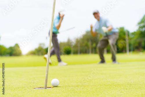 Asian man and elderly father are enjoy playing golf together with a good time.