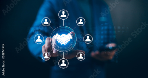 Businessman touches a handshake icon connected to a team network. Concept of Human Resource Management (HRM), team building, Customer Relationship Management (CRM), and business partnership.
