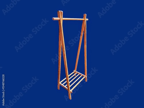 The dark blue background in the picture is a brown wooden clothes rack with four legs and a hanger that is a wooden rail with a wooden slot at the bottom used to put shoes or other things.