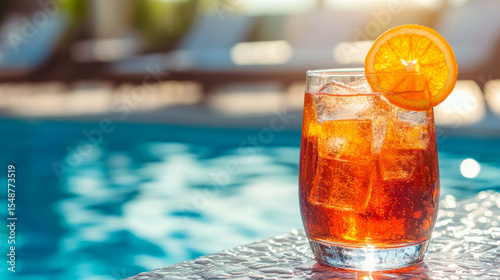 Sparkling aperol spritz with an orange slice rests elegantly by a resort pool, symbolizing leisure and upscale travel.