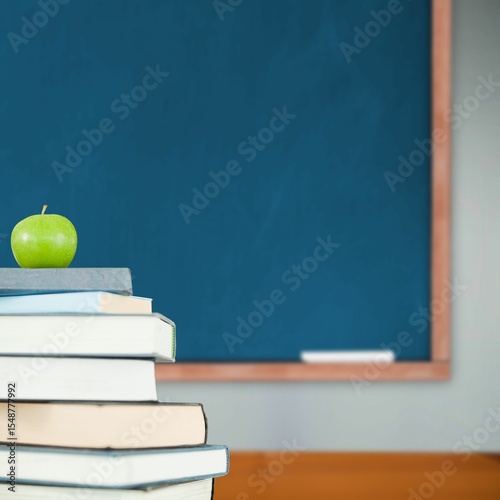 Green apple on pile of books in classroom