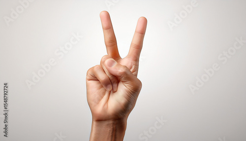 Un main qui fait un symbole de paix sur un fond gris.
