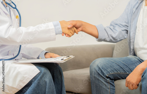 Male patient shakes hands with the doctor or female healthcare professional in hospital room