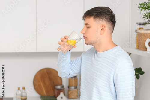 Young man drinking lemon in...