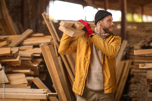 Male carpenter carrying woo...