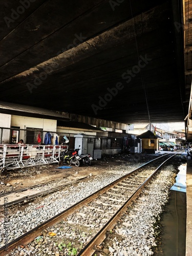 Underneath elevated railway tracks in a bustling Bangkok urban area