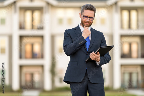 Realtor in suit. Rent or buy new home. Home insure. Property insurance promotion. Successful broker. Mortgage insurer. American sales manager. Real estate agent at house for sale. Skilled negotiator