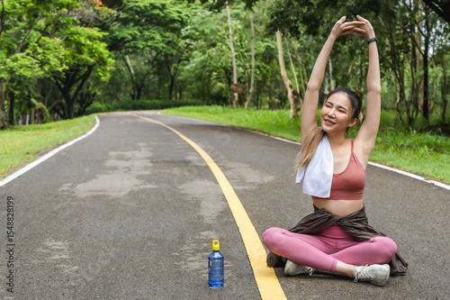 Asian sportswoman sitting and warm up before doing exercise in nature park