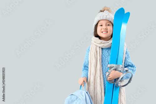 Little Asian girl with skis...