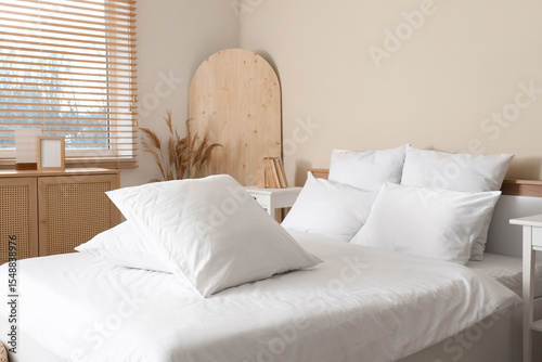 Cozy bed with white blanket and soft pillows in stylish bedroom, closeup