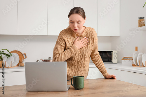 Obraz na płótnie Emotional young woman having panic attack at table in kitchen