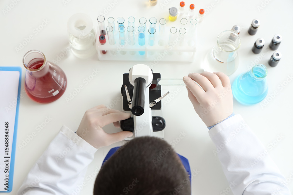 Fototapeta premium Male scientist with microscope working on table, top view