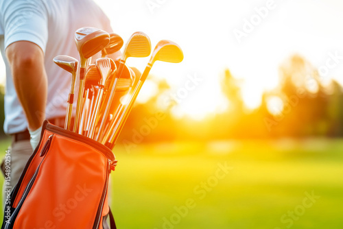 Golden Hour Tee Time: A golfer's vibrant orange golf bag, brimming with clubs, stands in sharp focus against the backdrop of a golden sunset. The scene evokes a sense of anticipation for the game.