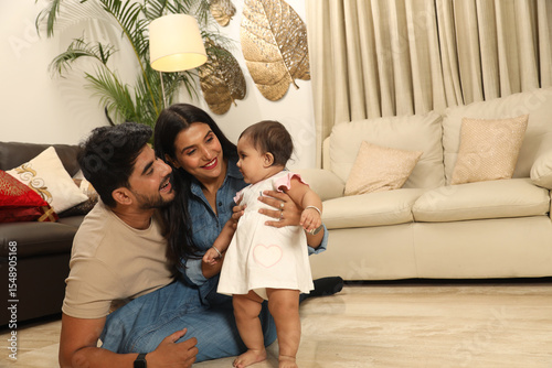 Fotografie Indian young couple with one infant child sitting on home