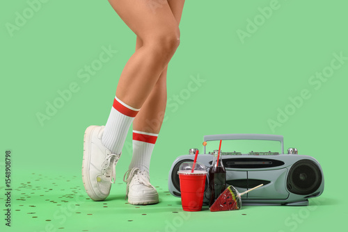 Photography Legs of woman with music player, soda and lollipop on green background