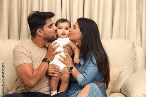 Fotografie Indian young couple with one infant child sitting on home