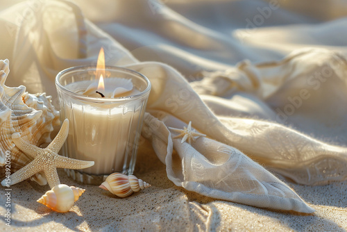 Aromatherapy candle with shell elements on towel over sand. Peaceful and cozy summer moment.