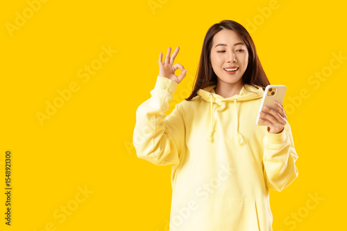 Young Asian woman with mobi...