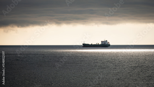 A silhouette of a oil tanker at sunset queuing up to dock at Milford Haven, Pembrokeshire, Wales