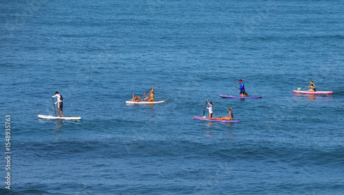 Company of young people  riding  on sup surfing in the sea at summer day