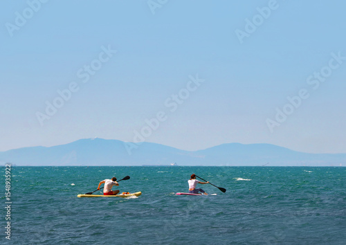 young couple   riding  on sup surfing in the sea at sumer time