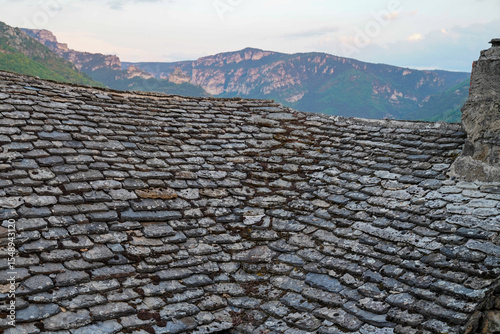 old stone tiled house roof in the south of France Aveyron with background mountains