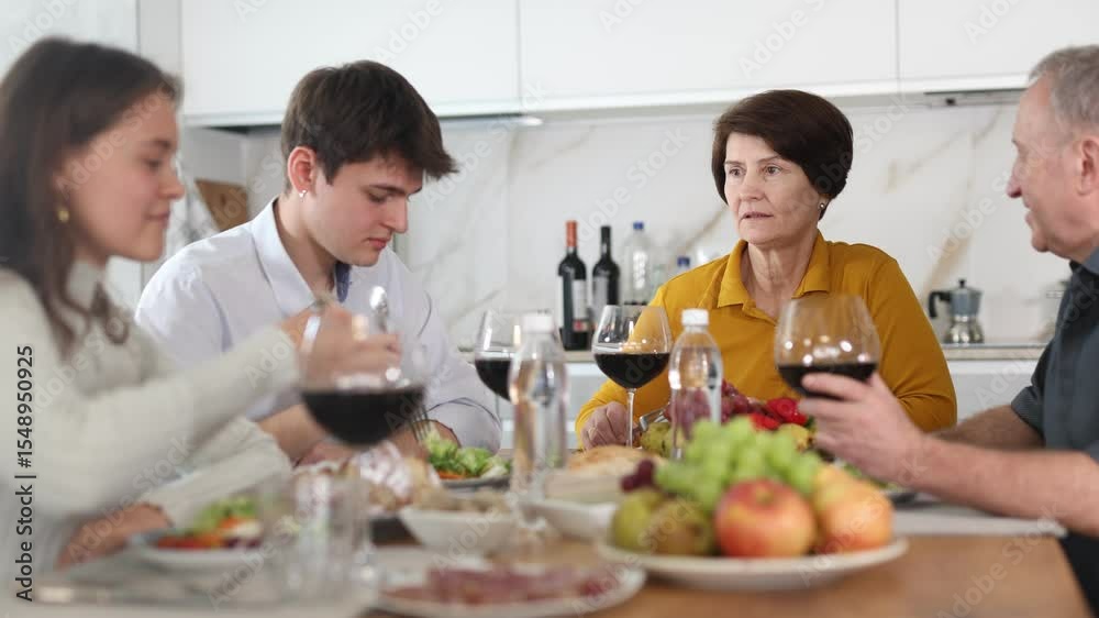 Father and mother together with adult children talking at the dinner table at home Father and mother together with adult children talking at the dinner table at home