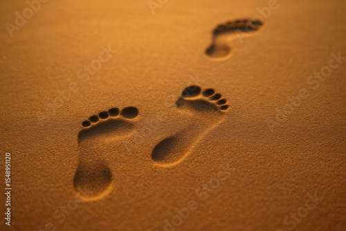 Footprints creating a path on golden sand at sunset