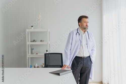 Wallpaper Mural Portrait of a confident and experienced male doctor standing in his modern medical office. A serious and thoughtful physician in a lab coat with a stethoscope, representing medical expertise. Torontodigital.ca