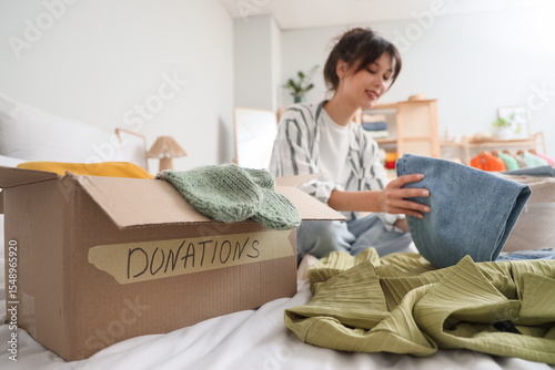 Young woman packing jeans f...