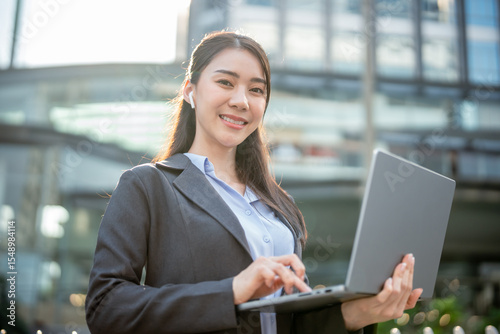 Portrait of Asian businesswoman wearing headphones while stand in city. Free Download Portrait of Asian businesswoman wearing headphones while stand in city. - GFXLoad