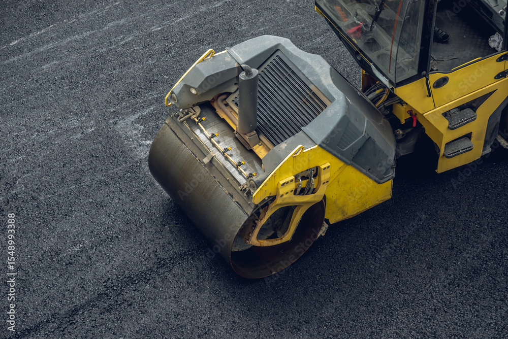 Fototapeta premium Workers lay a new asphalt coating using hot bitumen. Work of heavy machinery and paver. Top view