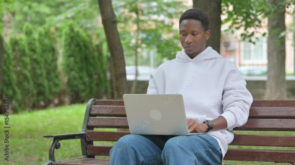 Young African Man Using Laptop Outdoor on Bench Young African Man Using Laptop Outdoor on Bench