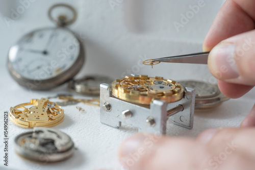 Close up of a professional watchmaker repairer working on an old vintage pocket watch in a workshop.