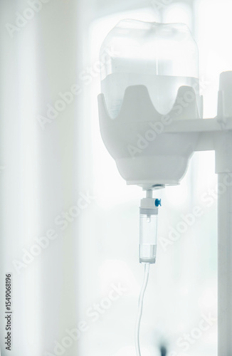 closeup of medical intravenous fluid drip chamber, hospital environment, sterile transparent container with clear liquid, tubing, healthcare treatment, emergency care, medical supplies
