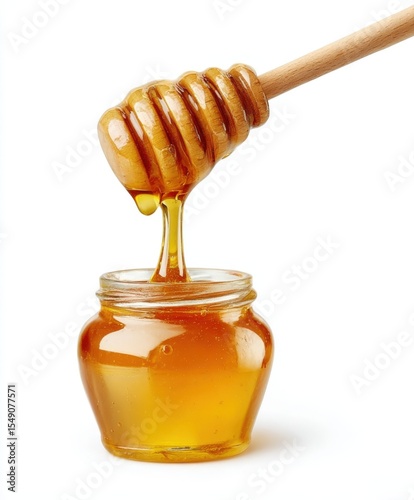 Close-up of honey dipper dripping honey into small glass jar with golden liquid