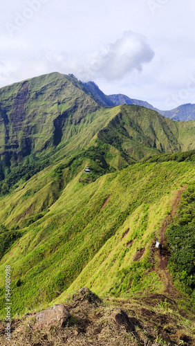 Summer mountain landscape with green grass and panoramic views of hills, trees, and sky