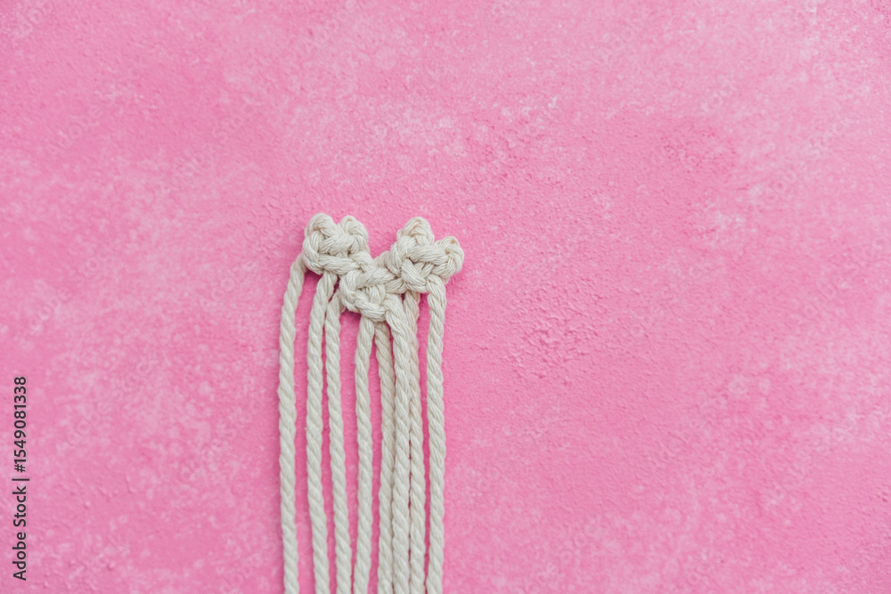 Obraz premium Macrame heart in progress on pink background