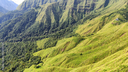 Summer mountain landscape with green grass and panoramic views of hills, trees, and sky