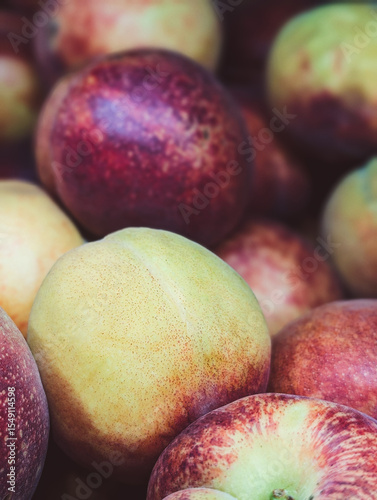 Vertical close-up of ripe red nectarines at a farmer’s market