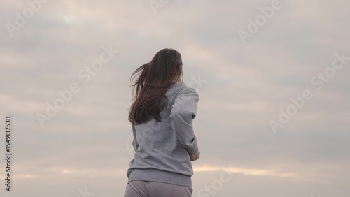 girl in sportswear runs against the sky at sunset, womens long-distance jogging, healthy lifestyle, cardio training for a slim figure and a healthy heart, striving to be first, run in morning at dawn.