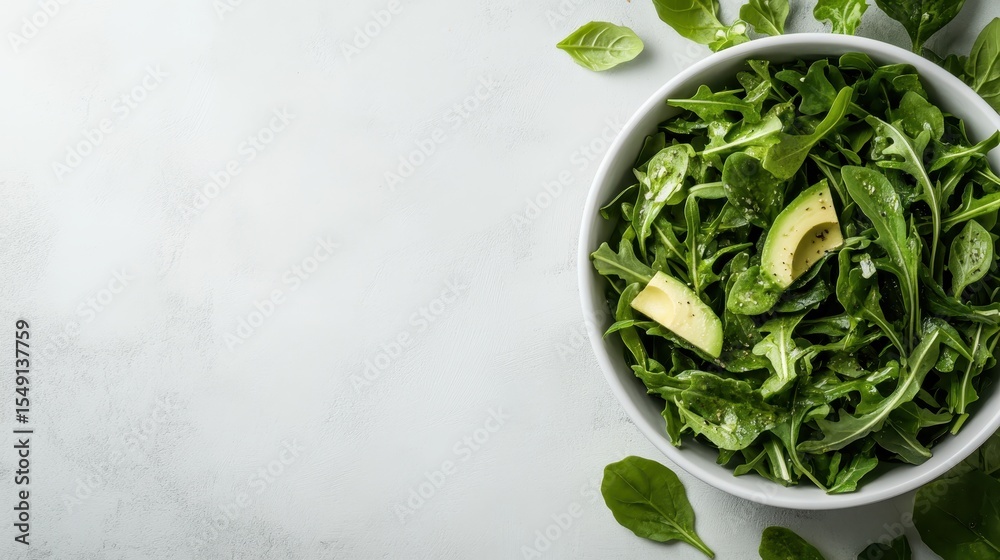 Obraz premium A healthy green salad featuring fresh spinach, arugula, and avocado slices, perfect for a nutritious meal or a fresh side dish.