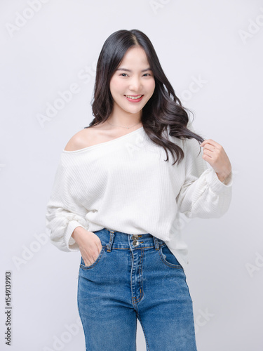 Half body portrait happy smile young asian beautiful woman curly hair wearing long sleeve shirt, blue jeans outfit, casual standing pose on white background joy positivity fashion lifestyle concept.