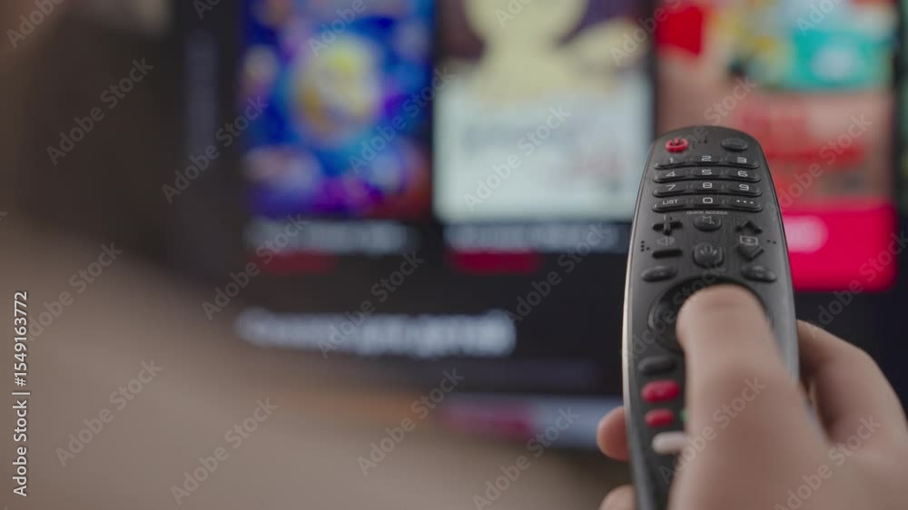 girl controls the TV remote control in room at home, rest on weekend, remote control of a modern smart TV, control TV and movie channels, close-up, blurred display screen, smart page scrolling device.